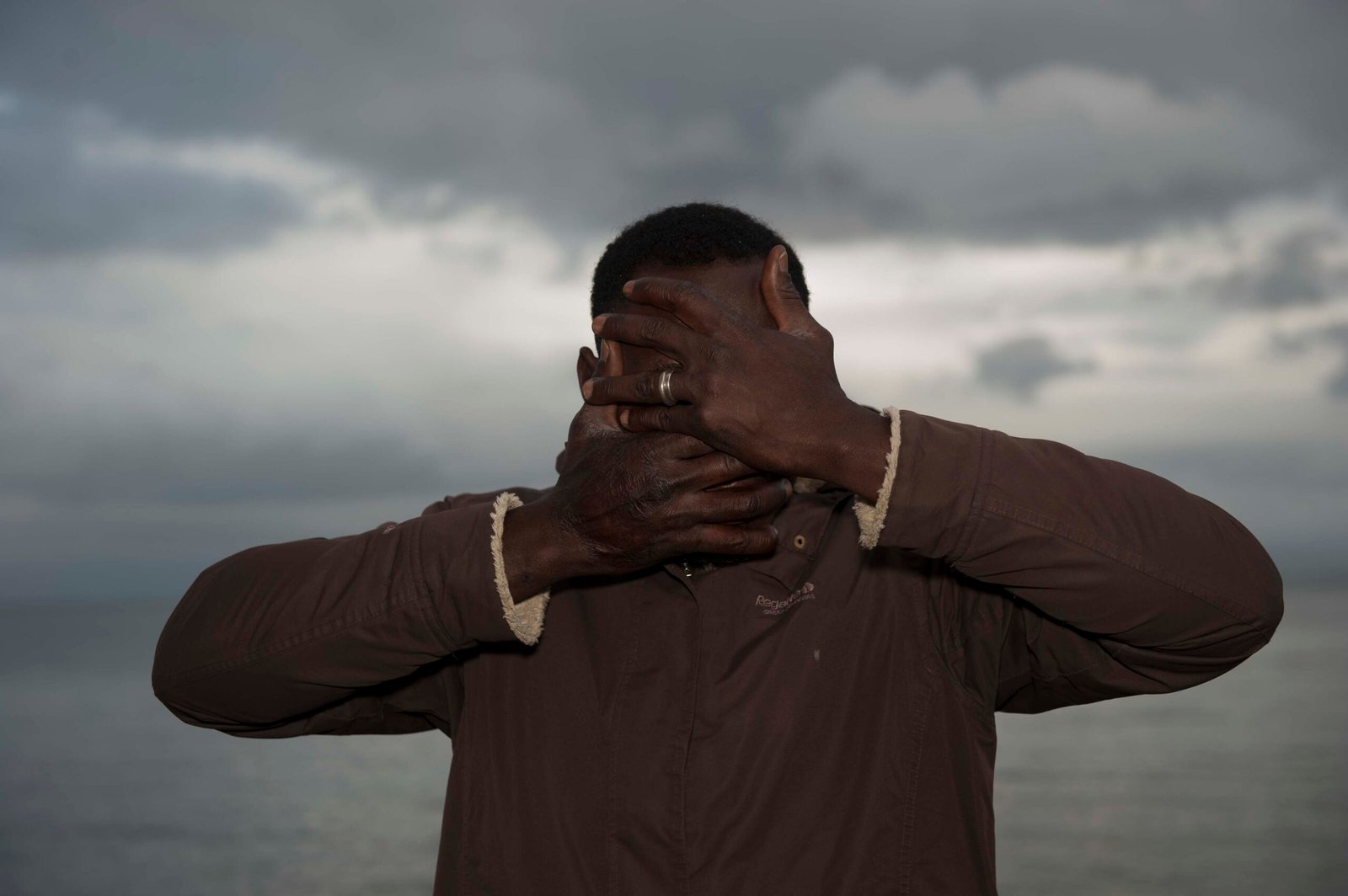 Man covering his face in front of the sea