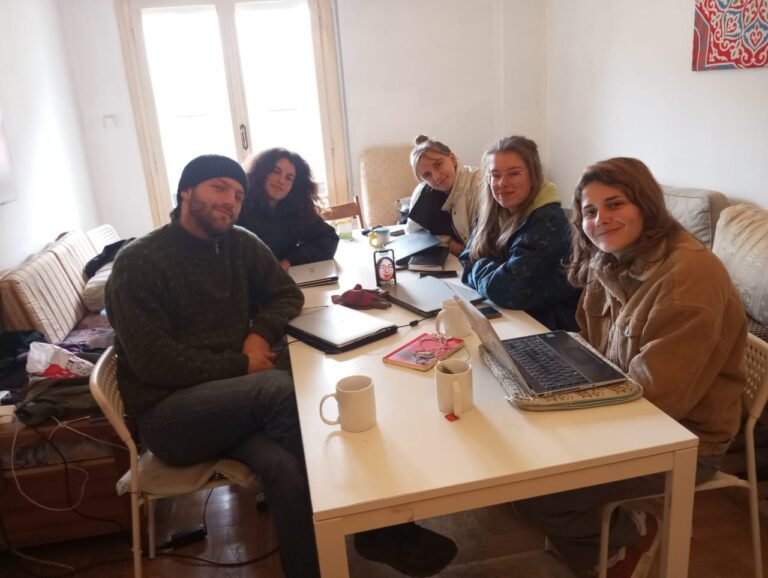 A photo from the KAST training session. Four attendees sit round a table, with Lucy leading the session.